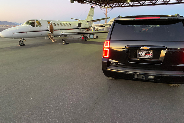 chevy suburban parked next to private jet